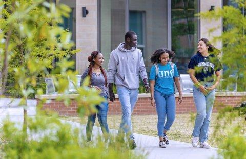 A group of students walking in front of Owens Ho使用 residence hall