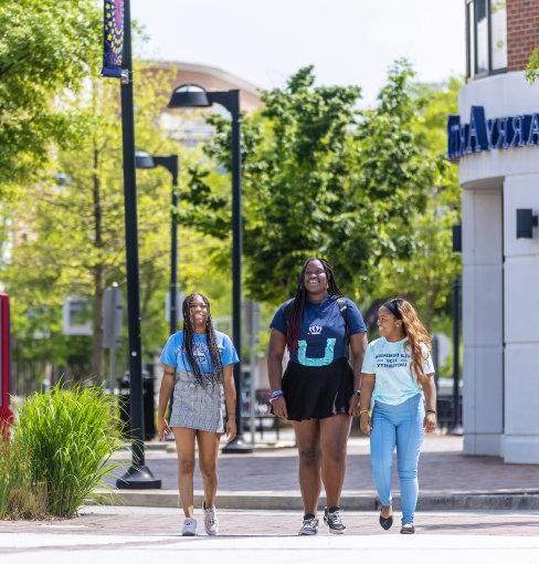 three female students wearing odu apparel are walking on monarch way